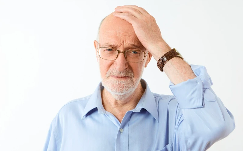 איש מבוגר עומד ושם יד על הראש