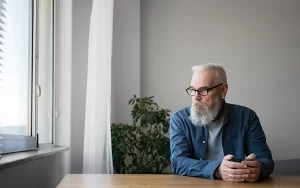גבר מחזיק ספל תה ומסתכל על החלון