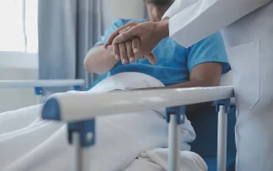 מטפל מחזיק את היד למטופל השוכב במיטה ותומך בו
